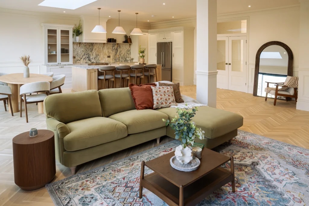Living area with a green sofa overlooking the Calacatta Monet marble kitchen in Sussex