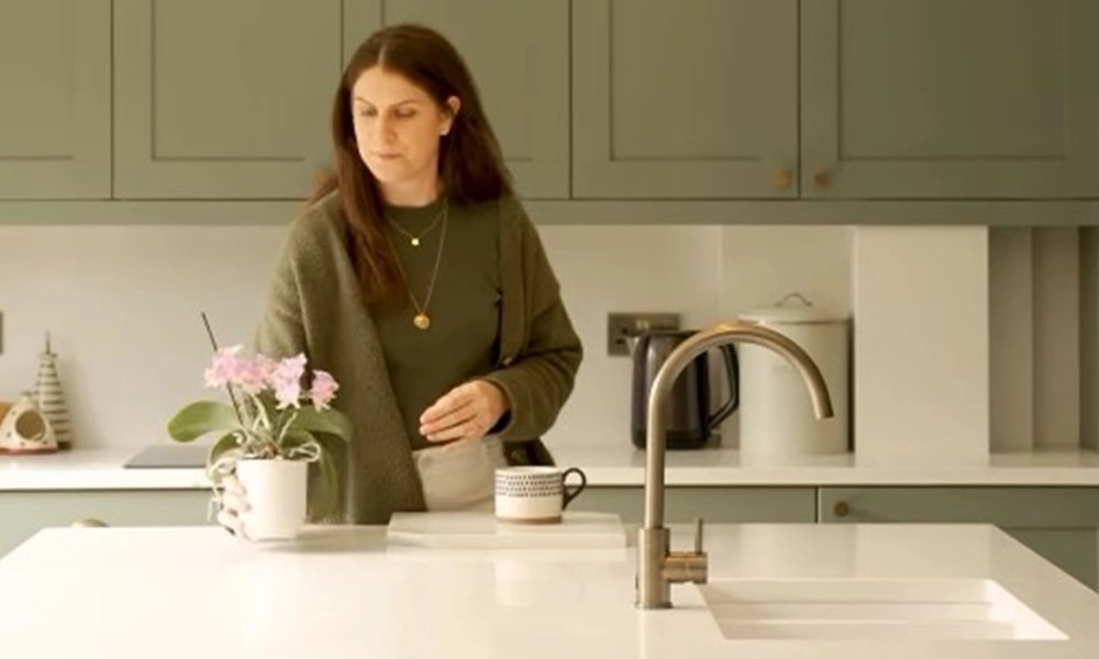 Sage Green Kitchen with Bianco Carrara Worktops 1 Woman arranging flowers beside Bianco Carrara worktops in a sage green kitchen