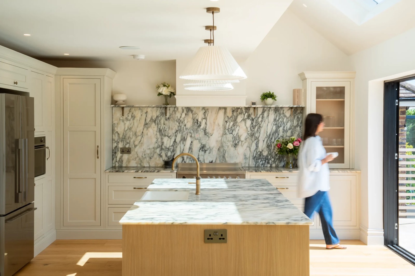Calacatta Monet marble worktops and matching splashback in a cream kitchen with a wooden island and brass tap in Hove