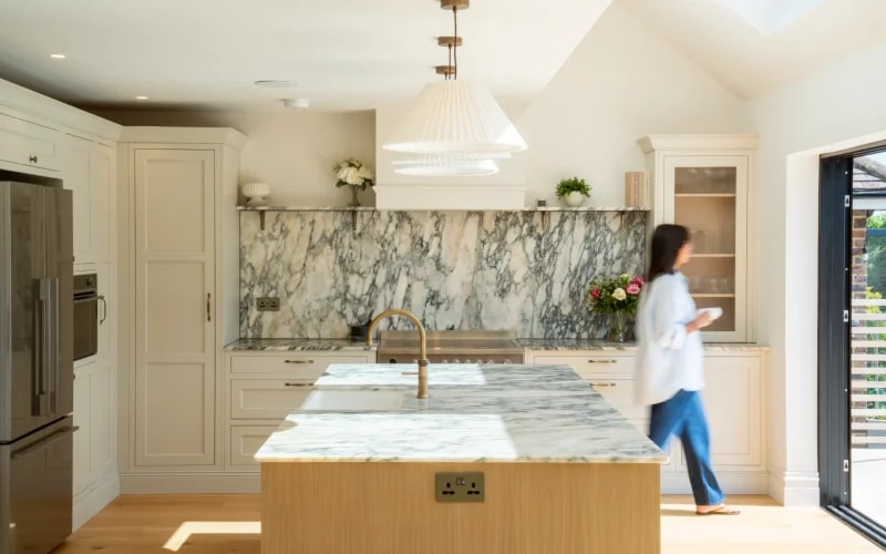 Calacatta Monet marble worktops and matching splashback in a cream kitchen with a wooden island and brass tap in Hove